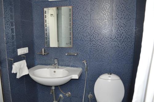 La salle de bains est pourvue de carrelage bleu, d'un lavabo et de toilettes. dans l'établissement Thyme the Transit, à Bangalore