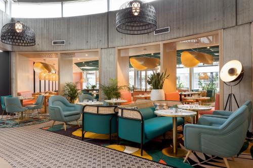 a restaurant with blue chairs and tables and windows at Novotel Paris Charles de Gaulle Airport in Roissy-en-France