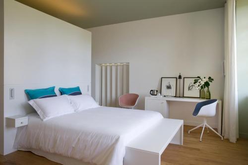 a white bedroom with a white bed and a desk at CHASSE-SPLEEN Les Chambres in Moulis-en-Médoc