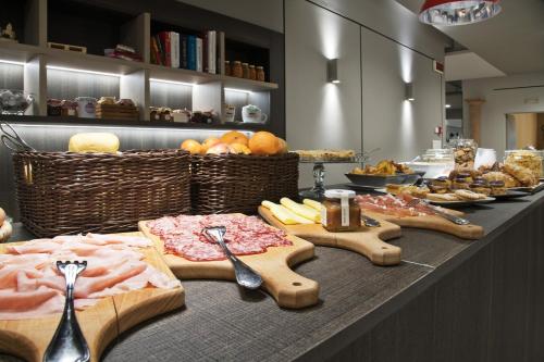 a buffet line with food and spoons on a counter at Hotel Bareta in Caldiero