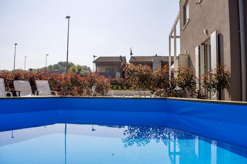 a blue swimming pool with chairs next to a building at Home Suites Home in Salionze