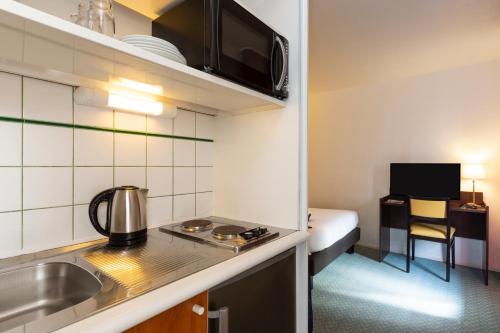 a small kitchen with a sink and a bed in a room at Aparthotel Adagio Access La Défense - Léonard De Vinci in Courbevoie