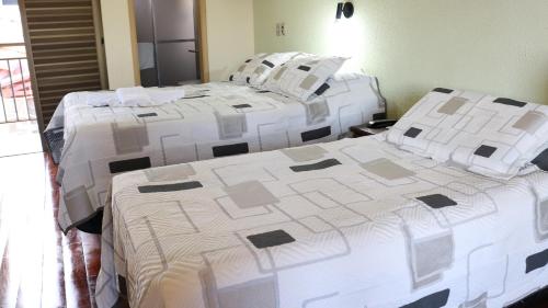 two beds in a room with white blankets and pillows at Café Palace Hotel in Três Pontas