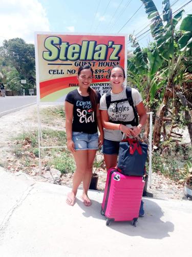 two women standing in front of a sign with luggage at Stella'z guesthouse in Siquijor