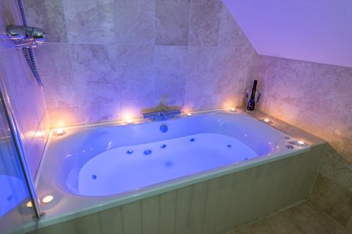 a bathroom with a tub with lights around it at Canaston Oaks in Narberth