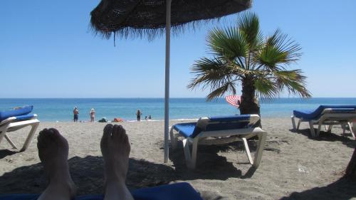 a person laying on the beach with their feet in the sand at Hostal Avalon in Nerja