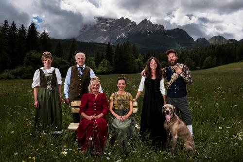 a family posing for a picture in a field with a dog at FIORI Dolomites Experience Hotel in San Vito di Cadore