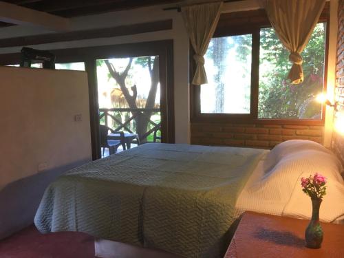 1 dormitorio con 1 cama y un jarrón con flores sobre una mesa en Las Acacias Apts Long Term Stays, en Ayampe