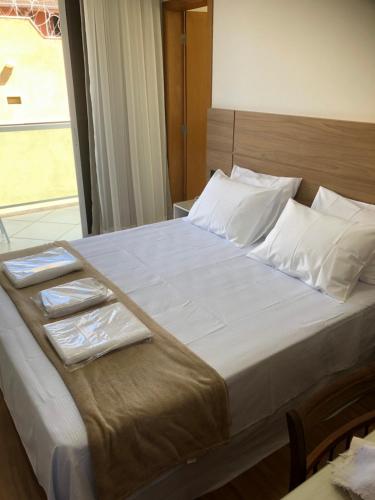 un grande letto con lenzuola bianche e asciugamani sopra di Flat de luxo em Lagoa Santa/MG a Lagoa Santa