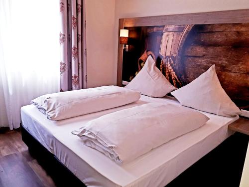 a bed with two white pillows and a wooden headboard at Brauereigasthof Dachsenfranz in Zuzenhausen