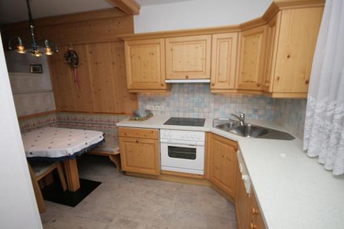 a small kitchen with wooden cabinets and a sink at Pension Trojerhof in Heiligenblut