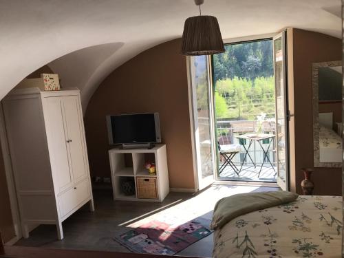 a bedroom with a bed and a television and a balcony at La Paramira in Pigna