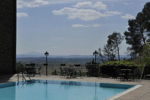 a swimming pool with tables and chairs and a view at Villa Schiatti in Cortona