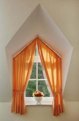 a window with an orange curtain and a vase of flowers at Waldhotel Forsthaus Remstecken in Koblenz