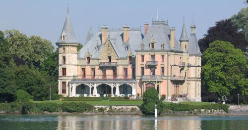 a castle sitting on top of a body of water at Schloss Schadau - Swiss Historic Hotel in Thun