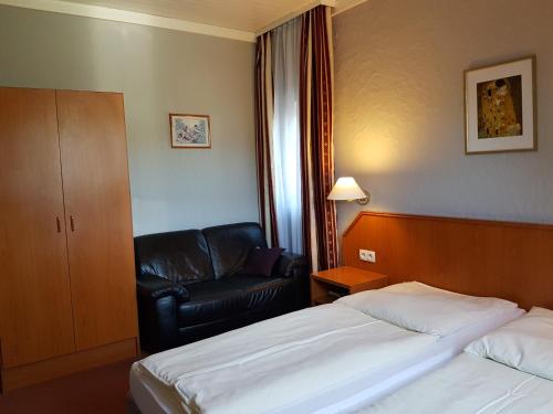a hotel room with a bed and a leather chair at Hotel Restaurant Klostermühle in Reutlingen