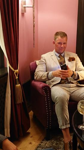 a man sitting in a chair looking at his cell phone at Garvaregården Hotel , B&B och Café in Askersund