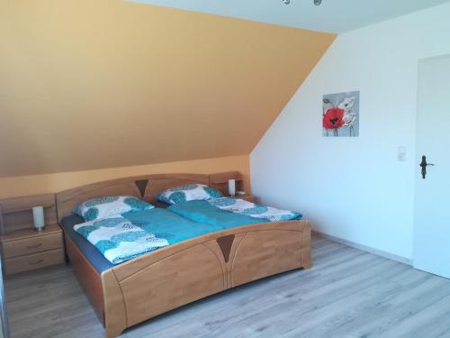 a bedroom with a wooden bed with blue sheets at Ferienwohnung am Riedrain in Eichenzell