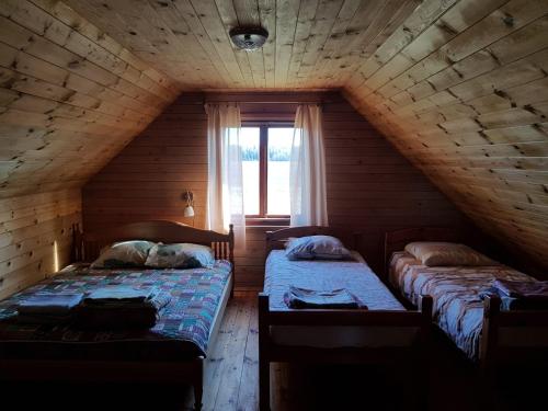 Pirmie Zaļmeži في جوركالني: سريرين في غرفة خشبية مع نافذة