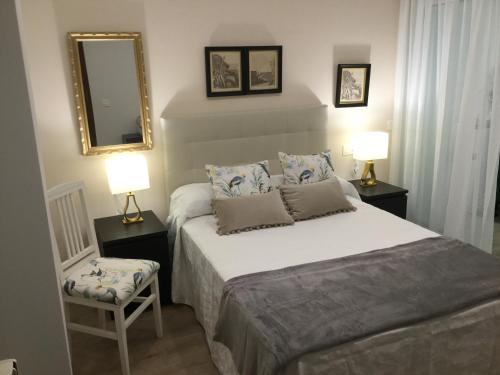 ein Schlafzimmer mit einem Bett, einem Spiegel und einem Stuhl in der Unterkunft Apto. Jesuitas in Gijón