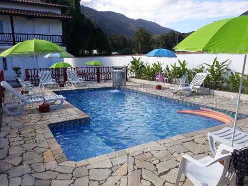 a swimming pool with lawn chairs and umbrellas at POUSADA TANI COM AR E PISCINA em MARESIAS in Maresias