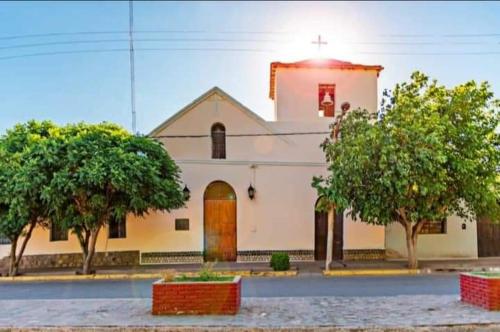 Una gran iglesia blanca con árboles delante. en Hospedaje Guandacol en Guandacol