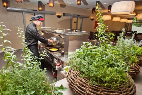 a man cooking in a kitchen with plants at Hotel Astoria Superior in Bled