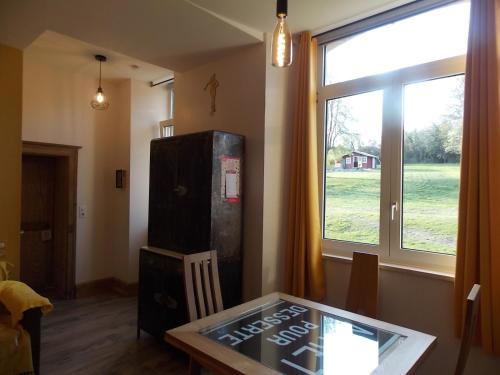 a living room with a glass table and a refrigerator at Les Gîtes De Morville in Malaumont