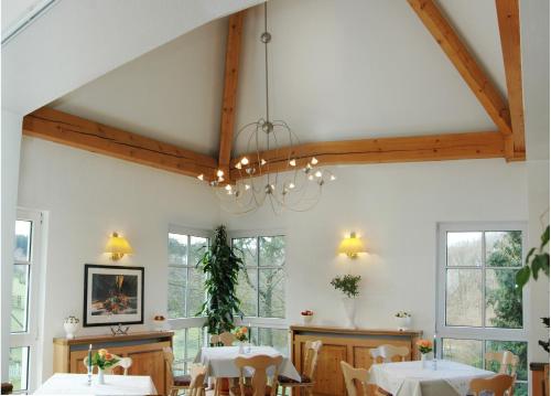 a dining room with white tables and windows at Waldhotel Forsthaus Remstecken in Koblenz
