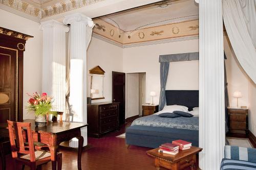 a bedroom with a bed and a desk and a table with a chair at Palazzo Ravizza in Siena