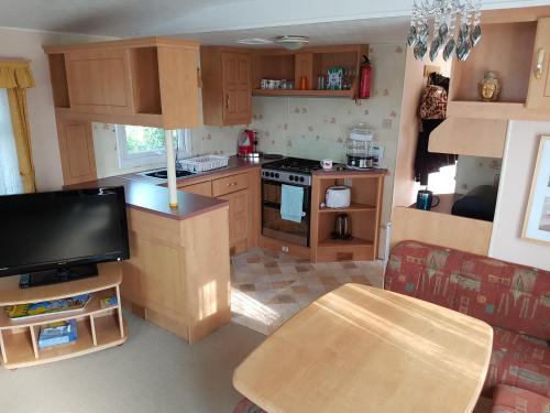 uma cozinha com armários de madeira, uma mesa e uma televisão em TP52 em Skegness