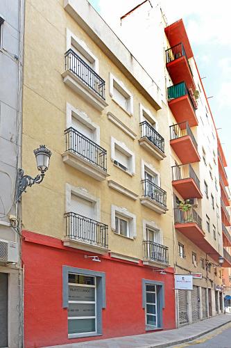 a orange and red building on the side of a street at Apartamentos Plaza,viviendas turisticas in Alicante
