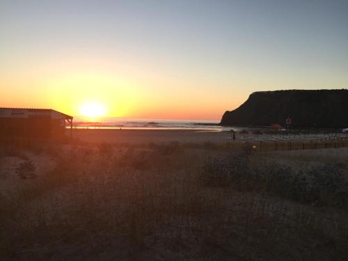 a sunset on a beach with the ocean at Casa Azul in Odeceixe