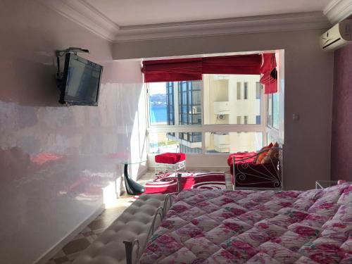 a bedroom with a bed and a tv and a window at la baie de Tanger in Tangier