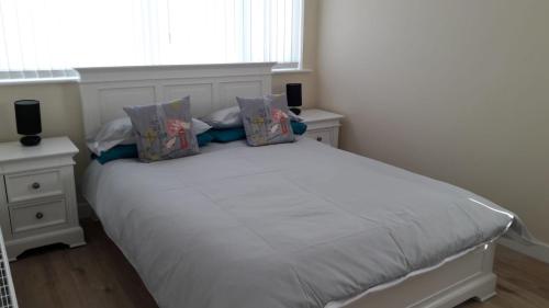 a white bed with pillows on it in a bedroom at 8 Queenora Avenue in Portstewart