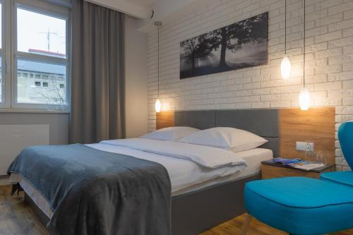 a bedroom with a bed and a blue chair at Native Apartments Augustiańska 24 in Krakow