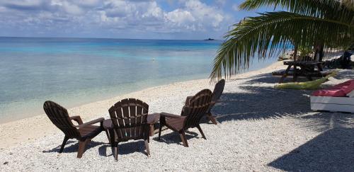 a beach with chairs, a bench, and a beach umbrella at Rangiroa Plage in Avatoru