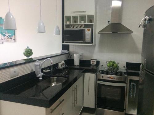 a kitchen with a sink and a stove at Golden Lake - Lindo Apartamento com Lagoa Privativa in Arraial do Cabo