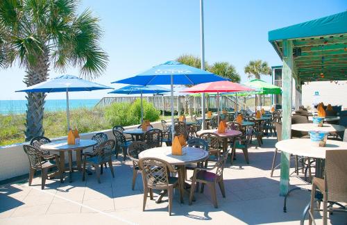 an outdoor patio with tables and chairs with umbrellas at Oceanfront Litchfield Inn in Pawleys Island
