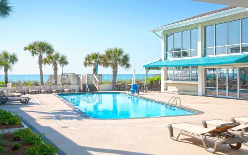 a swimming pool with chairs and a building at Oceanfront Litchfield Inn in Pawleys Island