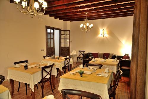 a restaurant with white tables and chairs and a chandelier at Casa Rural La Botica in Oropesa