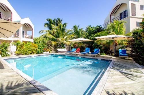 a swimming pool with chairs and umbrellas next to a building at Tres Cocos Resort in San Pedro