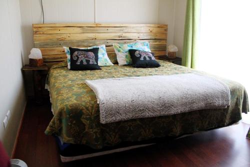 a bedroom with a bed with a wooden headboard and pillows at Casa Ollagua in Vicuña