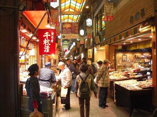 a group of people standing in a food market at Close to Golden temple -Kinkakuji- in Kyoto