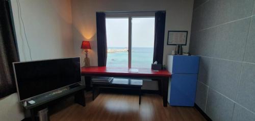 a room with a desk with a television and a window at Magenta in Donghae