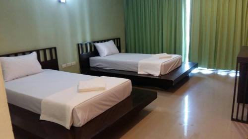 two beds in a room with green curtains at Krabi Home Town Boutique in Krabi
