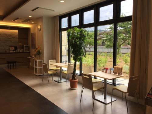 a restaurant with tables and chairs and a potted plant at Murayama Nishiguchi Hotel in Murayama