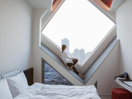 a woman sitting on a staircase in a room with a window at The Place Taichung in Taichung