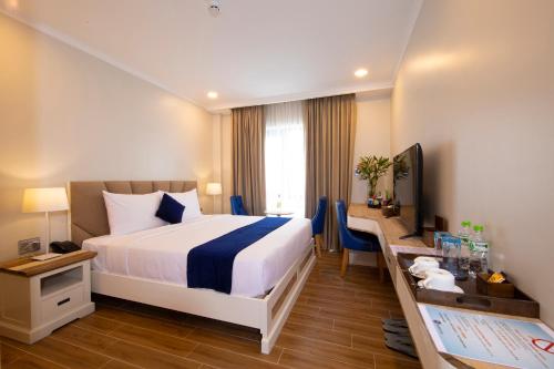 ein Hotelzimmer mit einem großen Bett und einem Schreibtisch in der Unterkunft Sabina Boutique Hotel 2 in Ho-Chi-Minh-Stadt