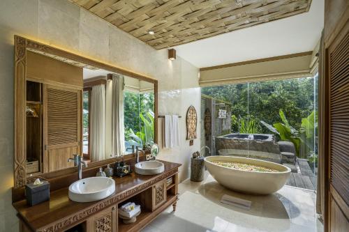 een badkamer met 2 wastafels en een grote spiegel bij The Kayon Jungle Resort in Ubud
